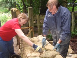 volunteers adding filling stones to a wall