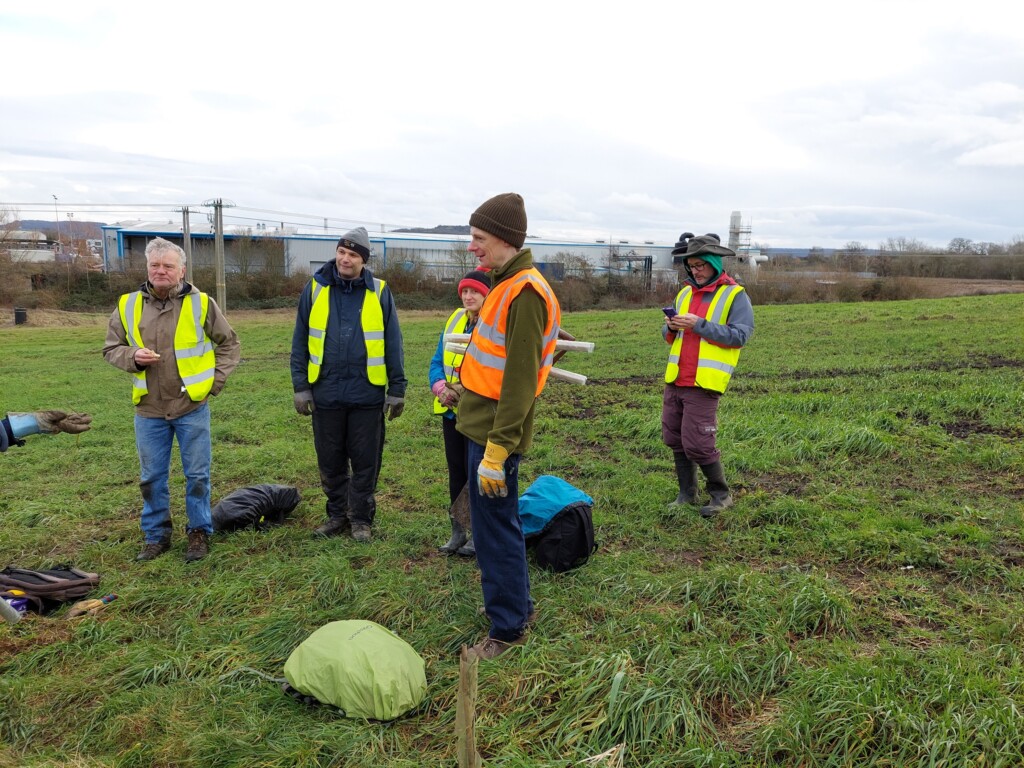 A group of people in safety vests standing in a field

Description automatically generated with medium confidence