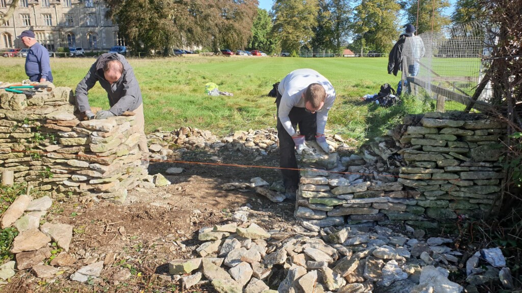 A couple of men building a wall

Description automatically generated